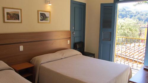 a bedroom with a bed and a large window at Pousada do Canto in Rio Acima