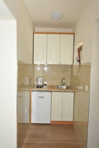 a small kitchen with white cabinets and a sink at Apartments Olive in Kotor