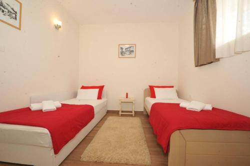 two beds in a small room with red sheets at Apartments Olive in Kotor