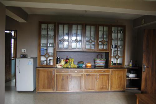 a kitchen with wooden cabinets and a white refrigerator at Vamoose Gomethang Homestay in Sosing