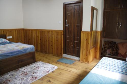 a bedroom with a bed and a closet and wooden floors at Vamoose Gomethang Homestay in Sosing