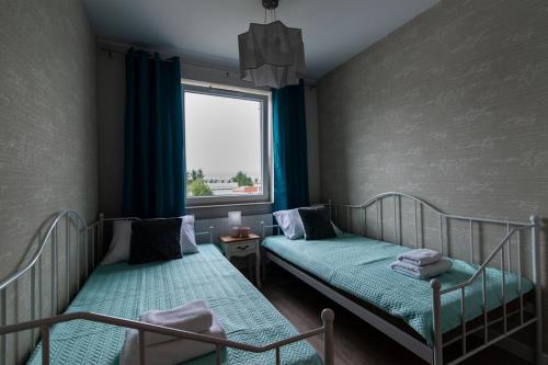 two beds in a small room with a window at Beżowe Love in Olsztyn