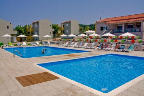 una piscina en un hotel con personas sentadas en sillones en Fournia Village, en Kyllini