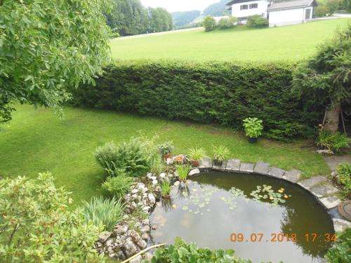 a pond with a stone bridge in a yard at Ferienwohnungen Josef & Karin Ketterl in Sachrang