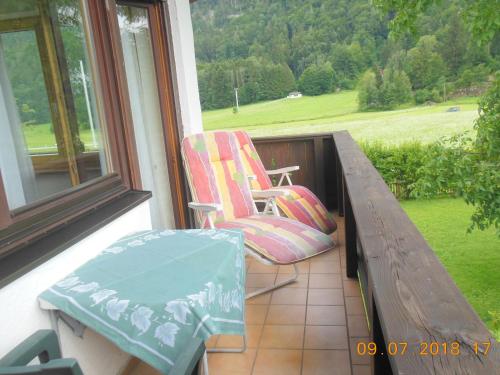 a porch with a bench and a chair and a table at Ferienwohnungen Josef & Karin Ketterl in Sachrang