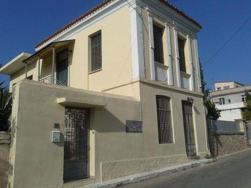 a white building with a door on a street at Aegina's Oasis in Aegina Town