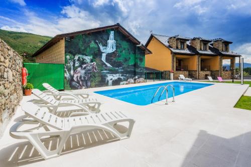 a swimming pool with two lounge chairs and a house at Apartamentos Rurales L´Abiseu in Caboalles de Abajo