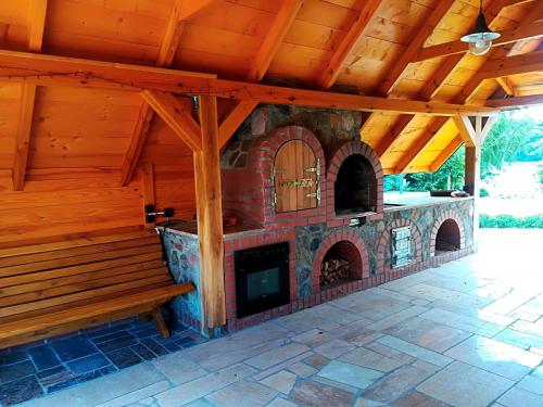 a patio with a brick fireplace and a wooden roof at Midom in Małdyty