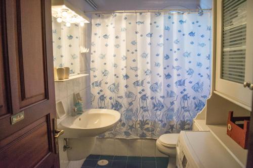 ein Badezimmer mit Waschbecken, Toilette und Duschvorhang in der Unterkunft Villa marina " G " in Argassi