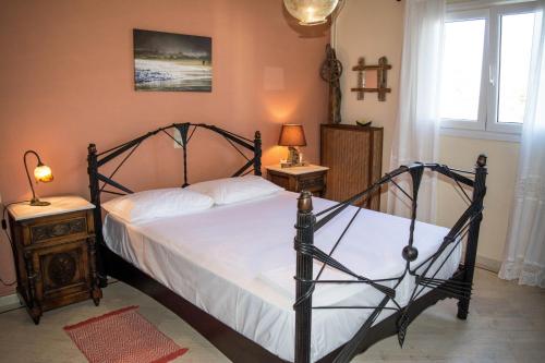 a bedroom with a bed with a black frame and white sheets at Villa marina " G " in Argasi