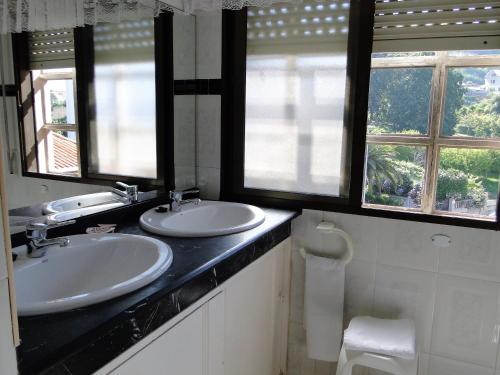 a bathroom with two sinks and two windows at Apartamentos Blanco in O Grove