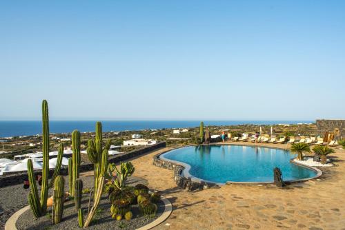een uitzicht op een zwembad met cactus en de oceaan bij Dammusi Sotto le Stelle in Pantelleria