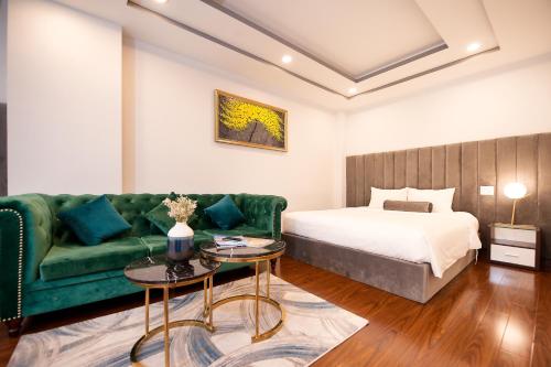 een woonkamer met een groene bank en een bed bij Adora Hotel in Ho Chi Minh-stad