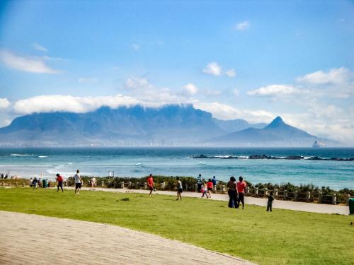 people walking on the beach with mountains in the background at Heaven on Earth - Blouberg Beachfront Self-catering Apartment in Bloubergstrand
