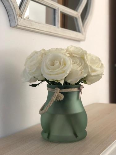 a green vase filled with white flowers on a table at Vila Guerreiro in Lagos