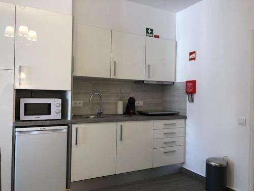 a kitchen with white cabinets and a microwave at Vila Guerreiro in Lagos