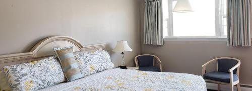 a bedroom with a bed with two chairs and a window at Gorham Motor Inn in Gorham