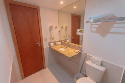 a bathroom with a toilet and a sink and a mirror at Salvador Business & Flat by Avectur in Salvador