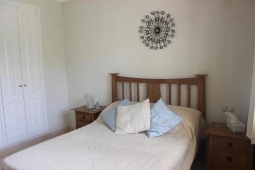 a bed with two pillows and a clock on the wall at Roda Golf & Beach Resort, Murcia in Roda