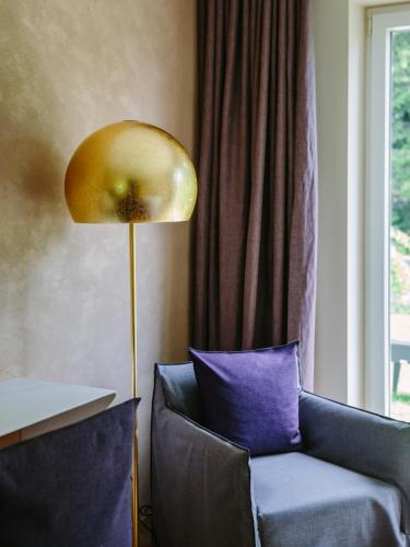 a gold lamp next to a blue chair with a purple pillow at Terra - The Magic Place Relais & Châteaux in Sarntal