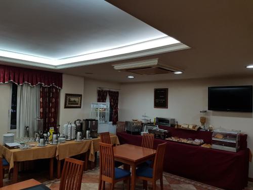 a dining room with tables and chairs and a tv at Hotel Camargo in Igollo