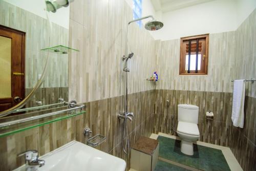 a bathroom with a shower and a toilet and a sink at Halcyon Rest in Hikkaduwa