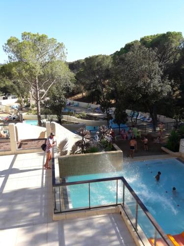 a resort swimming pool with people in the water at Mobil home florida - camping les cigales - 4 étoiles in Le Muy