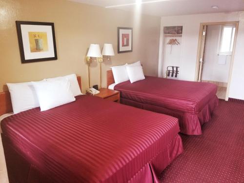 duas camas num quarto de hotel com lençóis vermelhos em Americas Best Value Inn-Williams/Grand Canyon em Williams