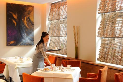 a woman standing in a dining room with tables at Hotel Blauer Bock in Munich