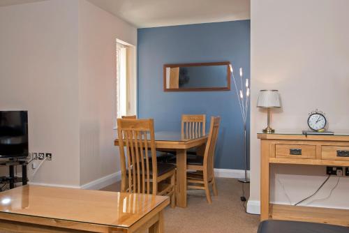 a dining room with a table and chairs and a blue wall at Riverview Apartment in Durham