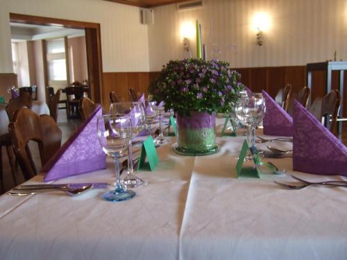 a table with wine glasses and a vase of flowers at Hotel Rose in Georgsmarienhütte