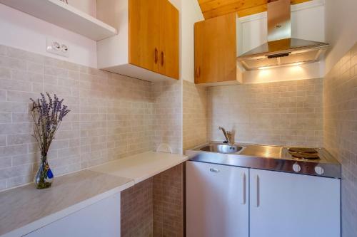 Elle comprend une petite cuisine avec des placards blancs et un évier. dans l'établissement Apartments Ruka - free barbecue, à Mali Lošinj