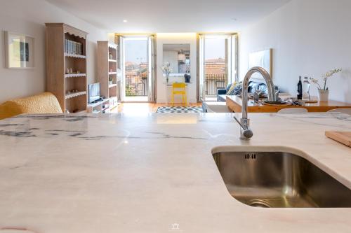 a kitchen with a sink and a living room at Merc Porto Vitoria's Place in Porto