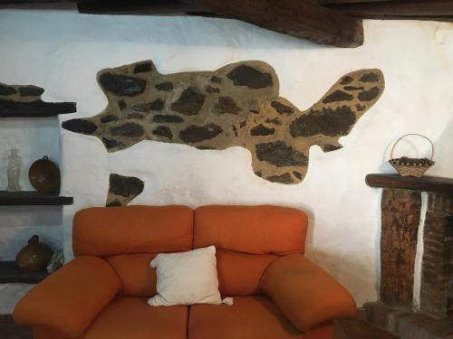 Un sofá marrón contra una pared con una vaca. en Casa La Puente, en Jubrique