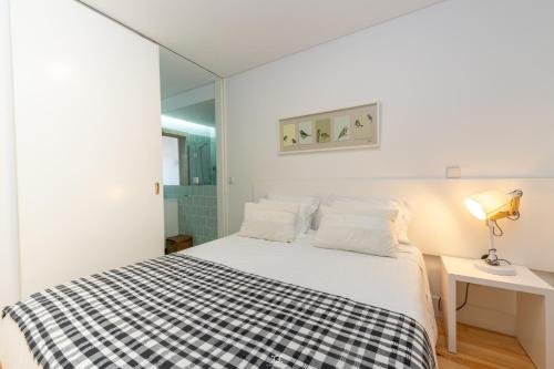 a bedroom with a bed with a black and white checkered blanket at Merc Porto Vitoria's Place in Porto
