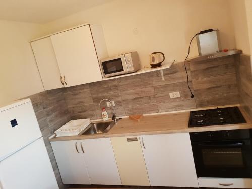 a small kitchen with a sink and a microwave at Apartments Šeherzada in Pula