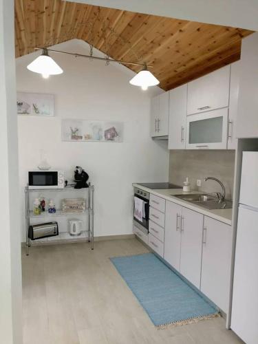 a kitchen with white cabinets and a sink and a stove at Casa do Relógio in Horta