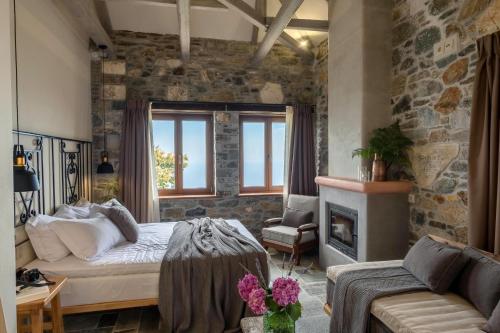 a bedroom with a bed and a stone wall at Adama Villas & Guesthouses in Mouresi