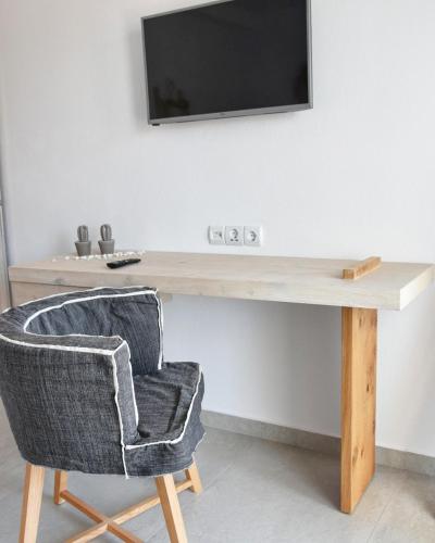 a desk with a chair and a television on a wall at Angelos Boutique Suites in Patitiri