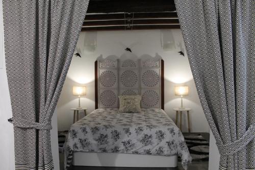 モンサラーシュにあるCasa da Muralha Suíteのベッドルーム1室(ランプ2つ、カーテン付)