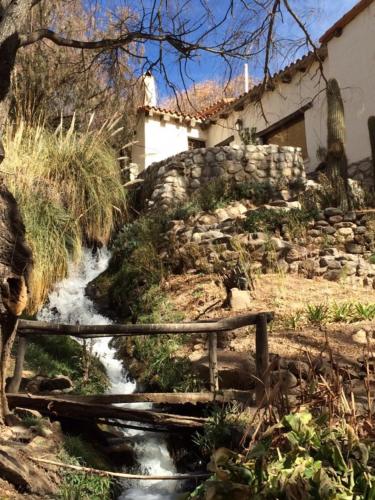 a creek in a garden with a bench and a building at El Molino de Cachi in Cachí