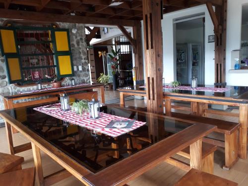 Ecohotel Bordones في Isnos: غرفة طعام مع طاولات خشبية وطاولة زجاجية