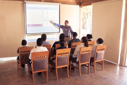 a man giving a presentation to a group of people in a room at Hotel Maioris Navolato in San Pedro