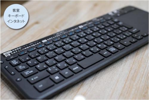 a computer keyboard sitting on top of a wooden table at Enoca Hotel in Fujisawa