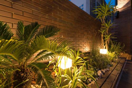 a brick wall with a bunch of plants and lights at Enoca Hotel in Fujisawa