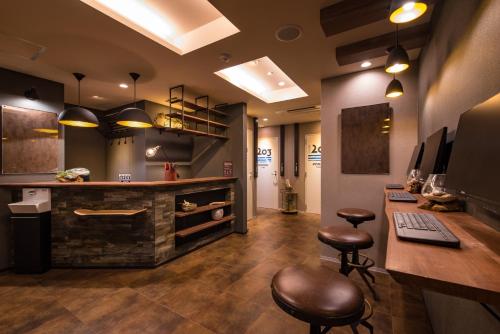 a room with a bar with stools and a desk at Enoca Hotel in Fujisawa