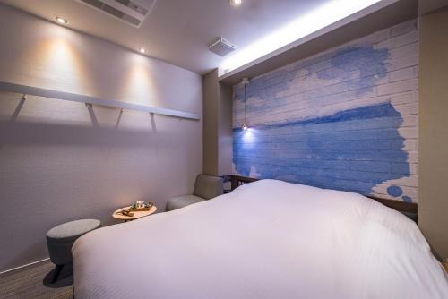a bedroom with a white bed and a brick wall at Enoca Hotel in Fujisawa