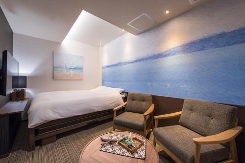 a hotel room with a bed and two chairs and a table at Enoca Hotel in Fujisawa
