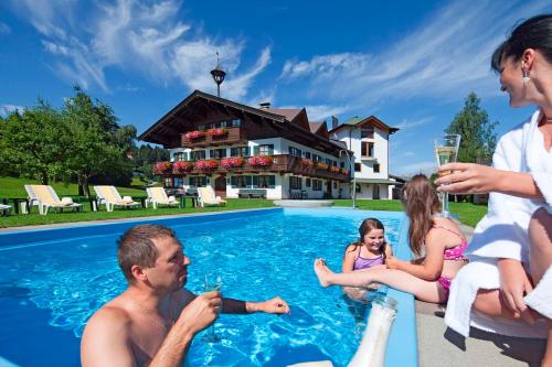 a group of people sitting around a swimming pool at Appartements Sonntal Einkehr in Fieberbrunn