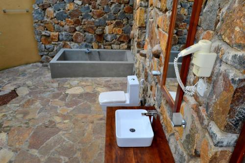 a stone bathroom with a sink and a bath tub at Kottawatta Village in Udawalawe